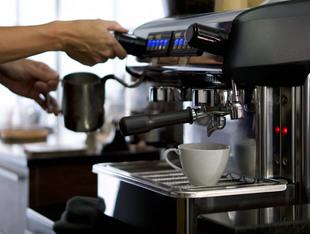 Professionelle Siebträgermaschine in einer Küche beim Zubereiten von Espresso mit Fokus auf die glänzenden Chromteile und den Siebträger.