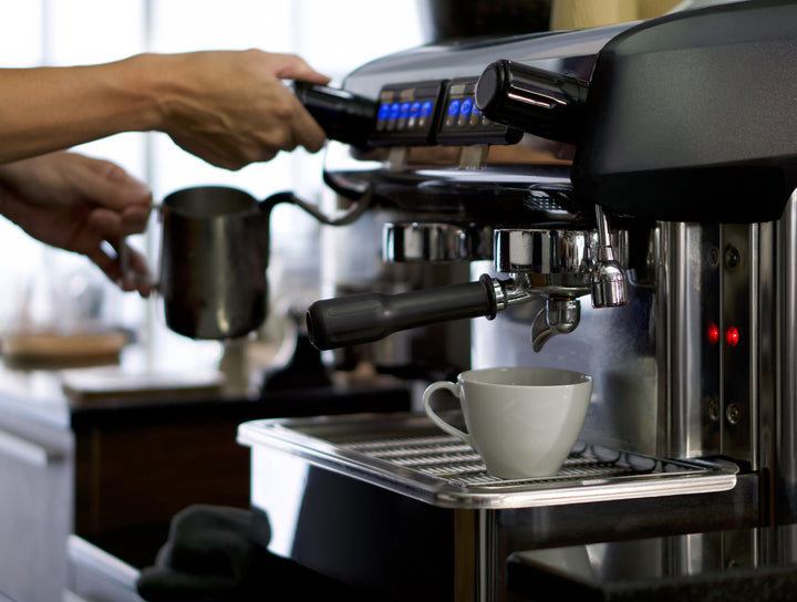 Professionelle Siebträgermaschine in einer Küche beim Zubereiten von Espresso mit Fokus auf die glänzenden Chromteile und den Siebträger.